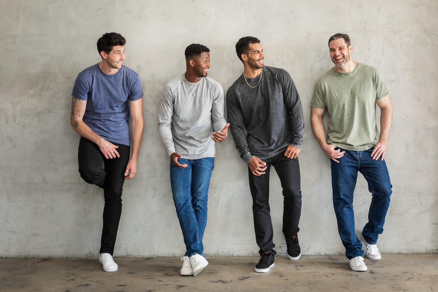 Four tall male models wearing black, navy, gray, and army Have It Tall vintage stone T shirts drier and washer safe tee while leaning against a wall