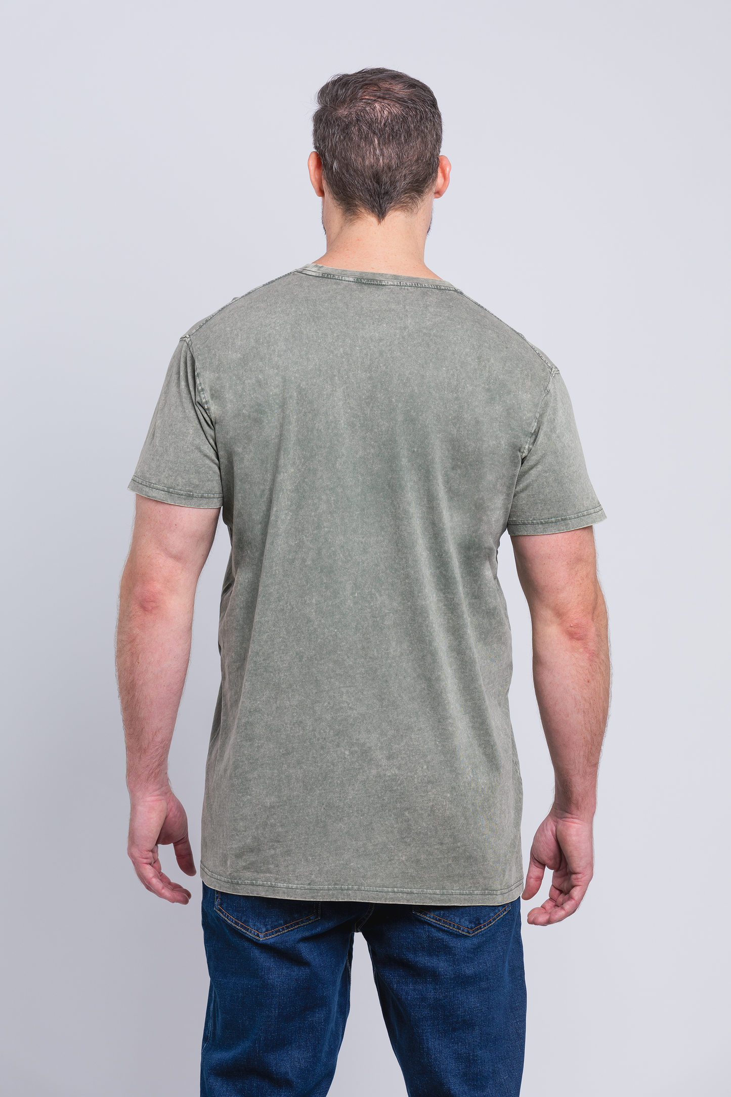 Tall male model 6,2 wearing a medium army Have It Tall vintage stone washed T shirt drier and washer safe tee showing the back of the shirt against a white background